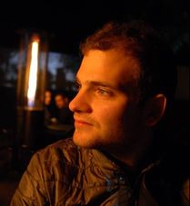 A man dimly lit looking to the left.