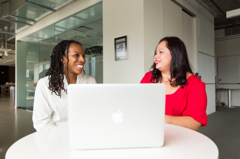 Two women talking in front of a computer