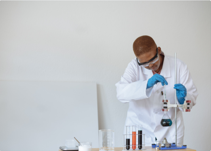 A Black woman in a white lab coat doing research with vials and beakers