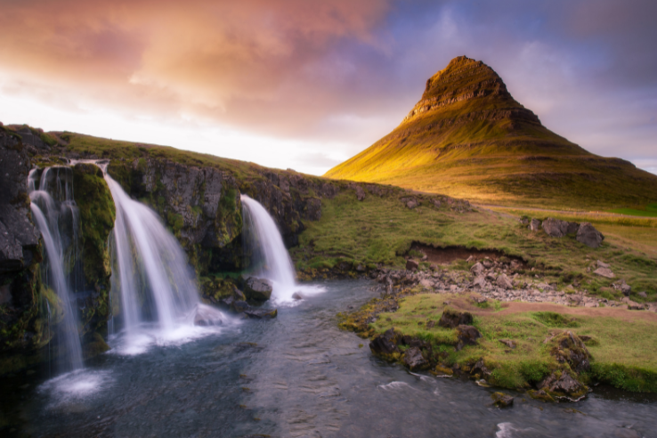 A Beautiful sunrise over a small lake with waterfalls and a tall mountain