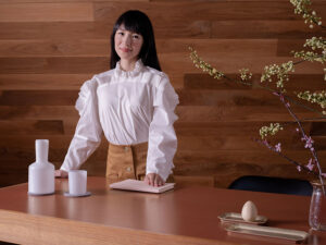 Marie Kondo standing near the head of a hardwood table
