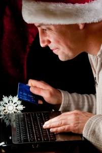 A man in a holiday santa hat doing online shopping