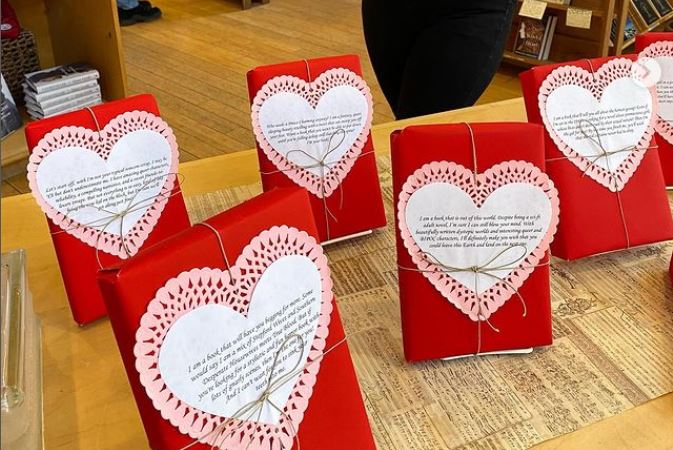 Books wrapped in red paper with a heart and brief description on the front