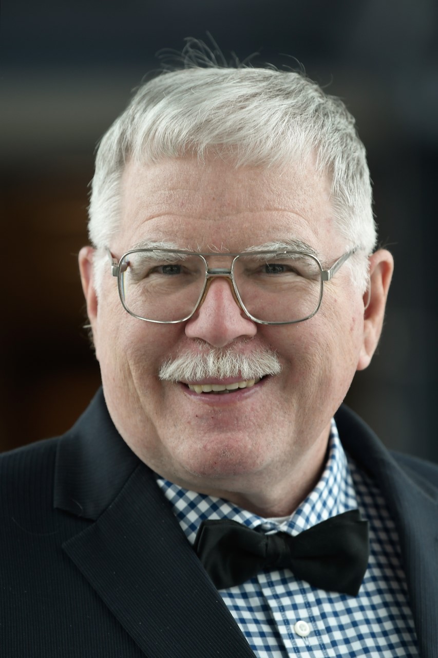 Dr. Charlie Robinson, a white man with a mustache, bowtie, and white hair