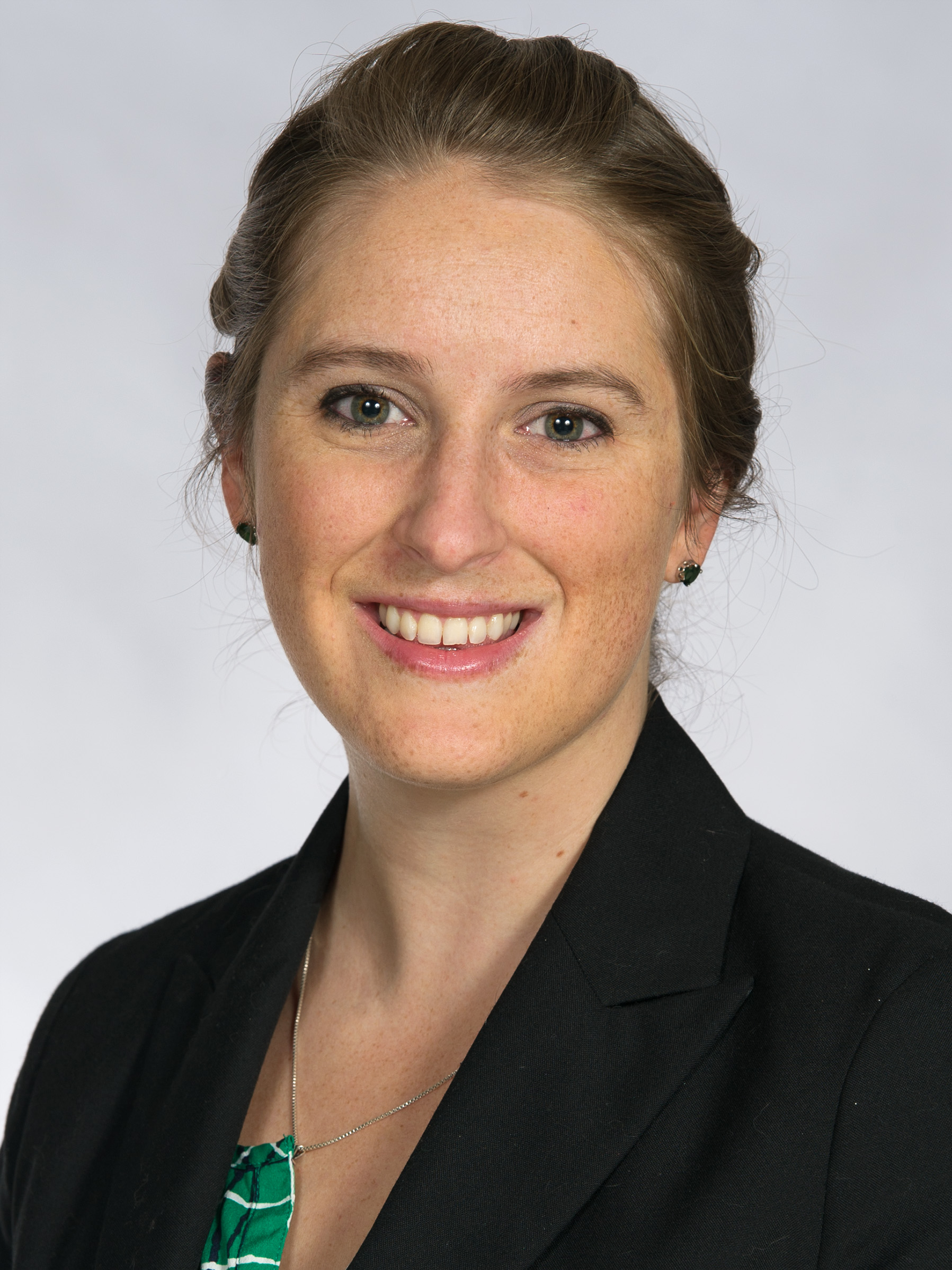 A white woman smiling wearing a dark blazer