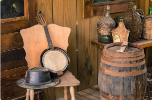 western themed porch with a barrel, bottles, and a hat and banjo on a chair