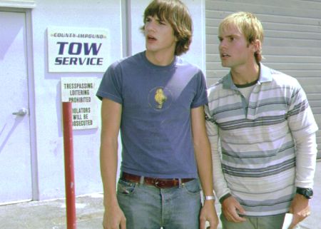 Two white guys looking for a car outside of tow service. 