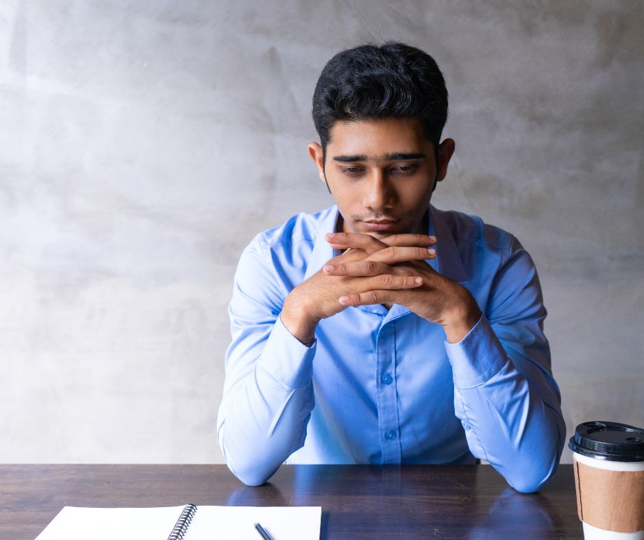 A sad looking Indian man in a blue shirt