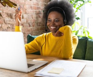 Woman, online, computer, brick, papers, notebook, yellow shirt, pencil
