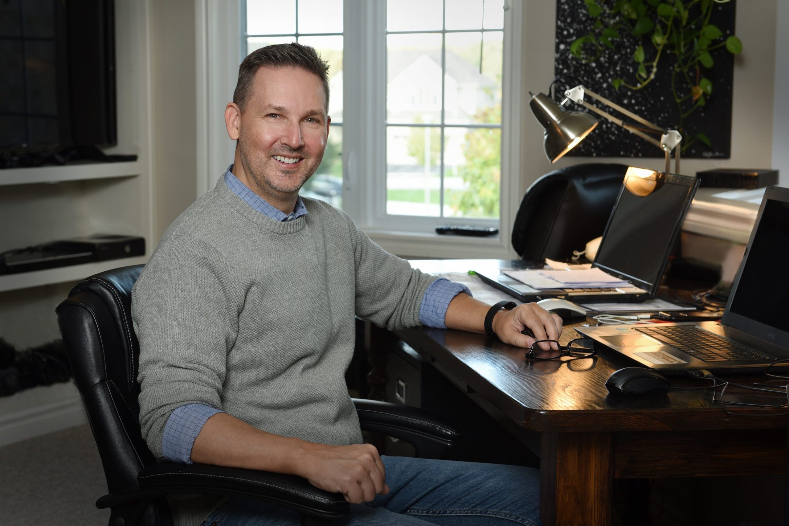 Timothy S. Johnston, desk, lamp, sweater, man, smiling