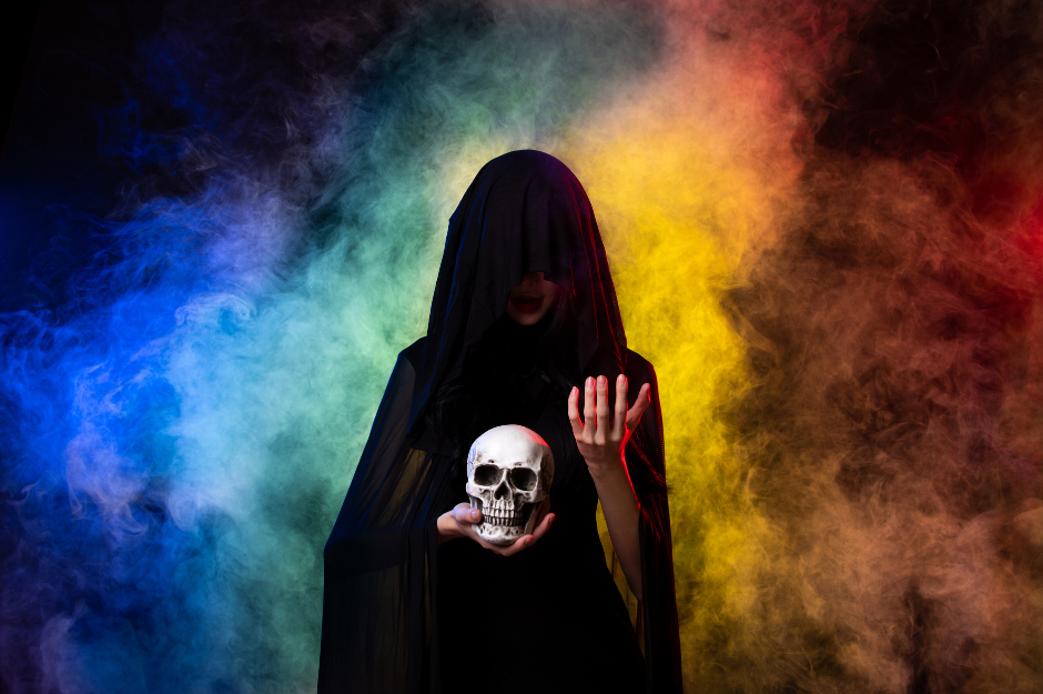 A spooky necromancer holding a skull with rainbow smoke. 